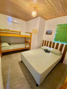 1 Schlafzimmer mit 2 Betten und einem grünen Fenster in der Unterkunft ((Casa brisa das águas)) Rota ecológica de milagres in Pôrto de Pedras