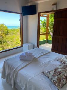 a bedroom with a large bed and a large window at Casa Lua Cheia in Praia do Espelho
