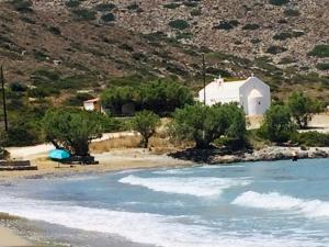 a small white church on a beach near the water at Kavousi Cottages - O Stavlos in Kavoúsion