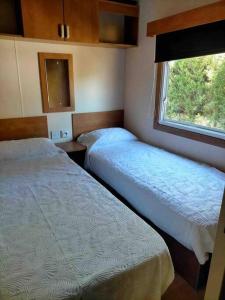 two beds in a small room with a window at Mobil home Calicanto in Masía Aldamar