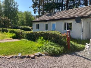 uma casa branca com uma caixa de correio em frente a um quintal em The Pines Self-catering cottage,Wester Ross, Scotland em Kinlochewe