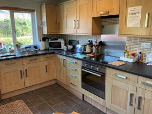 uma cozinha com armários de madeira e bancadas pretas em The Pines Self-catering cottage,Wester Ross, Scotland em Kinlochewe