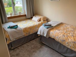 1 dormitorio con 2 camas y ventana en The Pines Self-catering cottage,Wester Ross, Scotland, en Kinlochewe