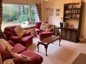 a living room with two red chairs and a table at The Pines Self-catering cottage,Wester Ross, Scotland in Kinlochewe