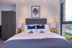ein Schlafzimmer mit einem großen Bett mit blauen Kissen in der Unterkunft City Cosy 1 bed - Perfect for Long Stays By Valore Property Services in Manchester