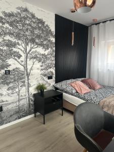 JugówにあるZielona Góra Apartamentのベッドルーム1室(ベッド1台、デスク、木の壁画付)