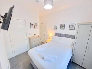 a bedroom with a white bed and a television at Burnley Terraced House by BEVOLVE - Free Parking 2 in Burnley