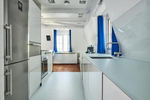 a kitchen with white cabinets and blue curtains at Hotel Max am See in Meersburg