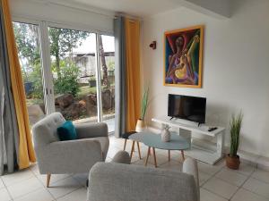 a living room with a couch and a tv at Les bungalows du château d'Ô in Deshaies