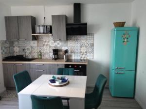cocina con mesa blanca y sillas verdes en Appartement 4 personnes vue mer à Santec au pied de la plage du Dossen en Santec