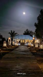 a boardwalk leading to a building at night at Luxury Camp Camelhouse in Merzouga