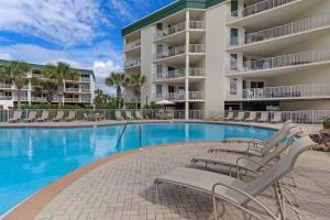 a swimming pool with lounge chairs in front of a building at Dunes of Seagrove A104 in Santa Rosa Beach