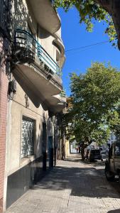 una calle vacía con un edificio y un árbol en en el corazón del Barrio Sur, en Montevideo