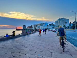 a man riding a bike on a sidewalk near the beach at en el corazón del Barrio Sur in Montevideo