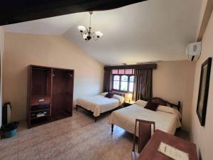 Sala de estar con 2 camas y mesa en Hotel Carmen, en Tarija