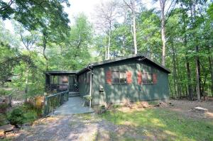 une cabine verte avec une terrasse couverte dans les bois dans l'établissement A Zen Mountain Retreat - Nirvana Awaits, à Baxter
