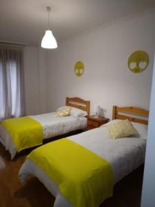 1 Schlafzimmer mit 2 Betten und gelber Bettwäsche in der Unterkunft A Las faldas del Tecla in A Guarda