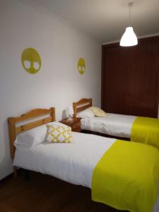 1 Schlafzimmer mit 2 Betten mit gelber und weißer Bettwäsche in der Unterkunft A Las faldas del Tecla in A Guarda
