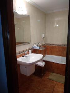 ein Badezimmer mit einem Waschbecken, einem Spiegel und einer Badewanne in der Unterkunft A Las faldas del Tecla in A Guarda