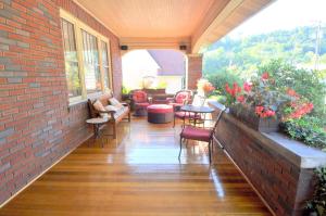 a porch with chairs and tables and a brick wall at Aunt Bea's Bungalow - Pet Friendly - Hot Tub - Screen Porch - Wifi - Fenced Yard - King Bed - Town in Berkeley Springs