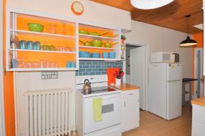 a kitchen with orange and white cabinets and a refrigerator at Aunt Bea's Bungalow - Pet Friendly - Hot Tub - Screen Porch - Wifi - Fenced Yard - King Bed - Town in Berkeley Springs