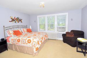 a bedroom with a bed and a chair and a window at Aunt Bea's Bungalow - Pet Friendly - Hot Tub - Screen Porch - Wifi - Fenced Yard - King Bed - Town in Berkeley Springs