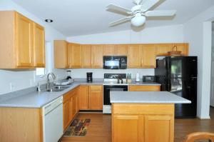 a kitchen with wooden cabinets and a black refrigerator at Cacapon Connected - Wifi, Fire Pit, Game Room, King Bed, Deck, Grill, Fireplace, Pet Friendly, Garage for mountain bike storage in Morton Grove