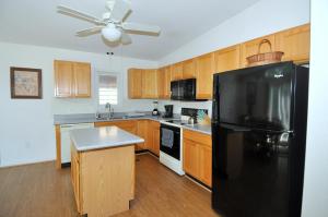 a kitchen with a black refrigerator and wooden cabinets at Cacapon Connected - Wifi, Fire Pit, Game Room, King Bed, Deck, Grill, Fireplace, Pet Friendly, Garage for mountain bike storage in Morton Grove