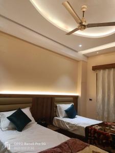 a bedroom with two beds and a ceiling fan at MR JaiSwaL DharMShalA in Sultānpur