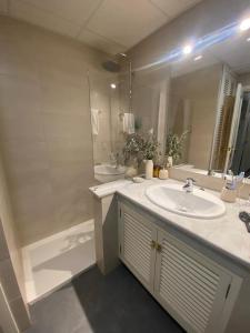 een badkamer met een wastafel, een spiegel en een bad bij Plaza España Familiar in Sevilla