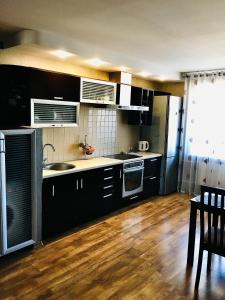 a kitchen with black cabinets and a wooden floor at Apartment on Shevchenka in Cherkasy