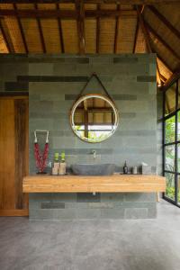 ein Bad mit einem Waschbecken und einem Wandspiegel in der Unterkunft East Bali Volcano View Resort & Spa - Adults Only Area in Karangasem