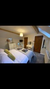 a bedroom with two white beds and a desk at Barn Cottage in Youlgreave