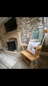 a rocking chair in a living room with a stone fireplace at Barn Cottage in Youlgreave