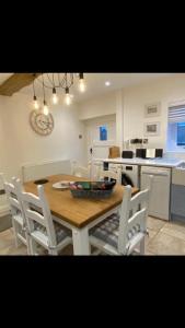 a kitchen with a wooden table and white chairs at Barn Cottage in Youlgreave