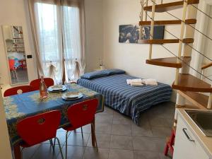 1 dormitorio con 1 cama y 1 mesa con sillas rojas en Casa Vacanze PETIT GARDA, en Raffa