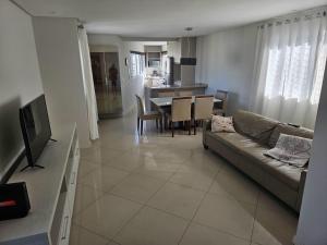 a living room with a couch and a dining room at Apartamento alto padrão no 16º andar com 3 quartos TOP in Balneário Camboriú
