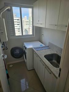 a small kitchen with a sink and a microwave at Apartamento alto padrão no 16º andar com 3 quartos TOP in Balneário Camboriú +29 photos