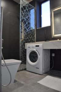 a bathroom with a washing machine and a sink at The Corner, Luxury One-Bedroom in Ras al Khaimah