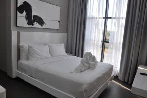 a white bed with a stuffed animal sitting on it at The Corner, Luxury One-Bedroom in Ras al Khaimah +2 photos