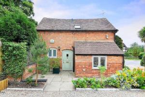 een rood bakstenen huis met een groene deur bij Quaint Victorian Coach House in village location in Great Alne