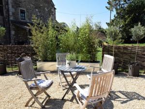 een patio met drie stoelen en een tafel met een plant bij Hares Barn in Trowbridge