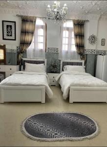a bedroom with two beds and a chandelier at La rose des sables 