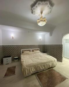 ein Schlafzimmer mit einem großen Bett und einem Kronleuchter in der Unterkunft La rose des sables 