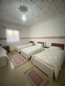 a bedroom with three beds and a ceiling at La rose des sables 