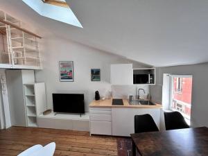 uma cozinha com armários brancos, uma mesa e uma televisão em Appartement - Carmes em Toulouse