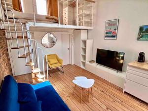 uma sala de estar com um sofá azul e uma televisão em Appartement - Carmes em Toulouse