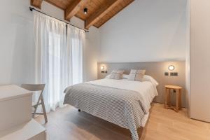 a white bedroom with a bed and a large window at Casa Lambda in Jaca
