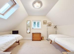 two beds in a attic bedroom with a window at Pears Grove - Southbourne in Emsworth
