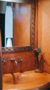 un vaso di fiori seduto su un lavandino con uno specchio di Riad Dar El Masa a Marrakech